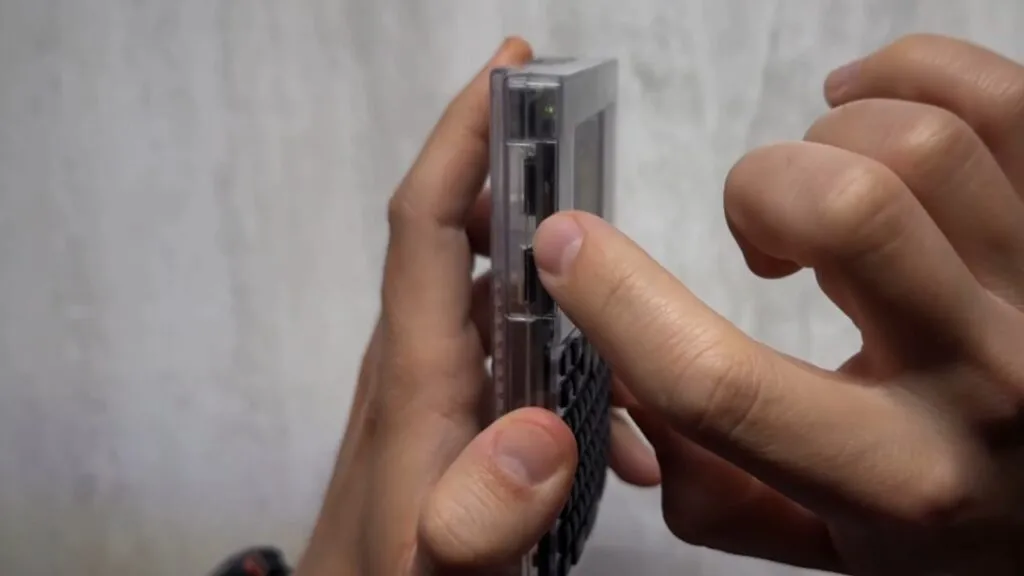 A person's hands holding and pressing a button on the side of a Coldcard Q Crypto Wallet.